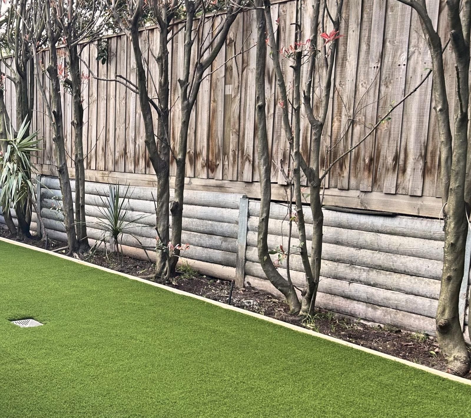 After: the same fence line with synthetic turf and timber edging, Burwood