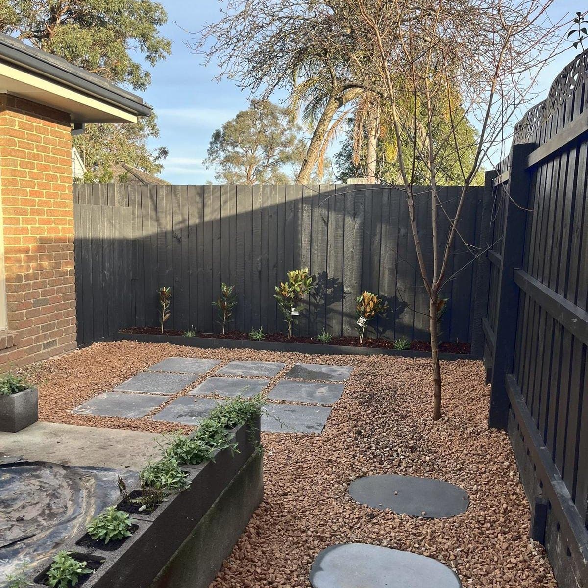 After: the same space as a gravel courtyard with square pavers, stepping stones and a planter, Forest Hill