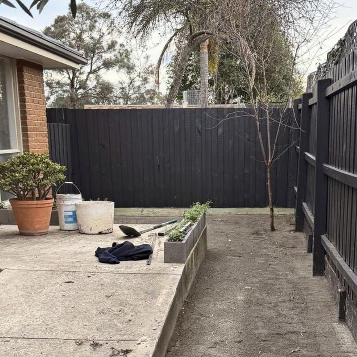 Before: a concrete path beside a bare dirt strip and a charcoal fence, Forest Hill
